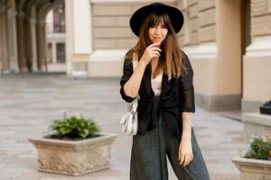 rue mode photo de élégant brunette femme dans décontractée tenue et noir chapeau. enjoing vacances dans européen ville.