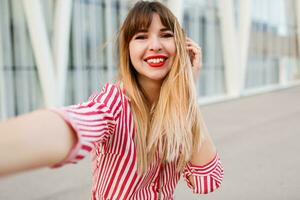 proche en haut portrait de content femme dans rouge robe posant sur le rue. photo