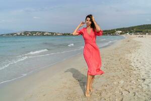 été image de content sexy femme dans magnifique rose robe posant sur le plage. plein longueur. photo