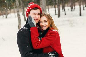 Jeune couple dans l'amour ayant amusement dans plus blanc forêt dans neige, embrassement et en riant. photo