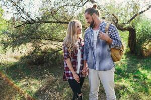 romantique branché couple en marchant dans ensoleillé été parc, chaud temps. Beau homme avec barbe et jolie mignonne blond femme profiter marcher. photo