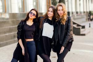 Trois jolie Jeune les filles ayant amusement en plein air ensemble . mode de vie Urbain ambiance. centre ville Contexte. meilleur copains portant noir décontractée tenue. photo