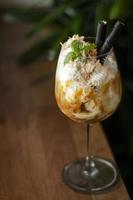 Noix de coco biologique gastronomique et caramel avec dessert sundae à la crème glacée dans un verre à vin photo