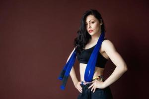 belle femme athlétique avec ceinture bleue sur le fond du mur photo