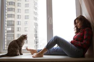 chat et fille sont assis près de la fenêtre photo