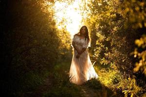 belle femme vêtue d'une robe blanche au coucher du soleil photo