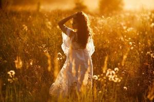 fille se tient dans un champ au coucher du soleil