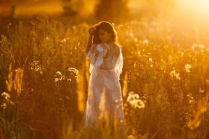 fille qui marche dans le pré au coucher du soleil photo