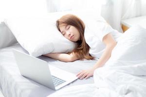 jeune femme asiatique avec ordinateur portable couché dans la chambre. photo