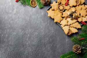 Noël traditionnel pain d'épice biscuits sur une assiette avec décoration, épices et Noël arbre branches sur foncé Contexte. Haut voir. copie espace. photo