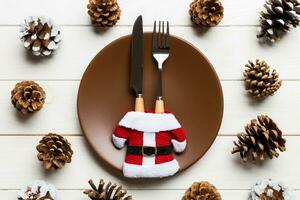 ensemble d'assiettes et d'ustensiles de nouvel an sur fond en bois. vue de dessus du dîner de vacances décoré de pommes de pin. notion de temps de noël photo