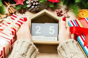 vue de dessus des mains féminines tenant un calendrier sur fond en bois. le vingt cinq décembre. décorations de vacances. concept de noël photo
