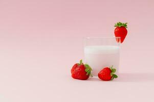 Créatif composition fabriqué de Lait boisson avec fraise goût dans verre tasse décoré avec rouge des fraises sur pastel rose Contexte. minimal smoothie ou Milk-shake concept. en bonne santé nourriture pour petit déjeuner. photo