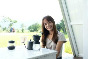 asiatique femelle touristique moudre et brasser café à boisson dans le Matin. photo