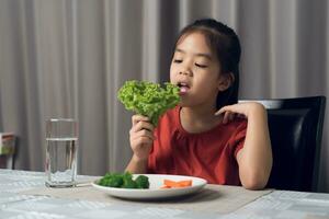 asiatique peu fille en mangeant en bonne santé des légumes avec goût. photo