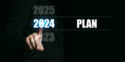 Nouveau année 2024 avec des plans. homme d'affaire montrer du doigt à le Nombres de le année à ensemble buts et fabrication des plans pour le à venir an. photo