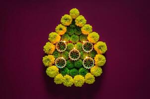 argile diya les lampes allumé à célébrer pour diwali Festival avec coloré fleurs ensemble comme flamme forme sur foncé violet Contexte. photo