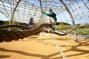 des gamins ayant amusement sur une enfants terrain de jeux sur une ensoleillé journée. photo