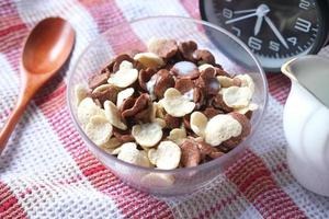 verser du lait dans des flocons de maïs aux céréales au chocolat dans un bol sur la table photo