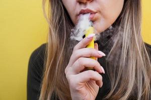 une jeune fille fume une cigarette électronique jetable photo
