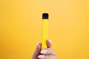 Cigarette électronique jetable jaune en main féminine photo