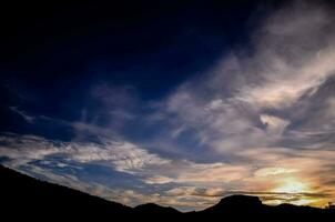 le Soleil ensembles derrière une nuage couvert Montagne intervalle photo