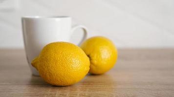 deux citrons sur la table de la cuisine près d'une tasse de thé blanc photo