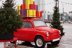 Voiture rétro rouge de Noël avec des coffrets cadeaux à l'extérieur photo