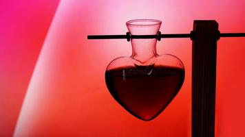 bouteille en forme de coeur ouverte de philtre d'amour rouge sur un arrière-plan flou photo