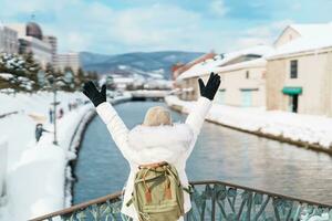 femme touristique visite dans otaru, content voyageur dans chandail tourisme Otaru canal avec neige dans hiver saison. point de repère et populaire pour attractions dans hokkaïdo, Japon. Voyage et vacances concept photo