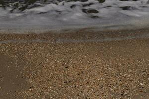 je aimé le Regardez de le océan à venir dans le plage ici. le mer mousse lentement la lessive plus de le jolie galets certains de lequel Regardez comme gemmes et sont translucide tout très lisse de étant dégringolé. photo