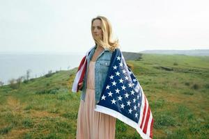 une fille vêtue d'une robe corail et d'une veste en jean tient le drapeau des états-unis photo