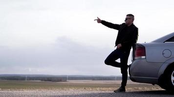 Sde vue d'homme d'affaires à lunettes assis sur le coffre de la voiture photo