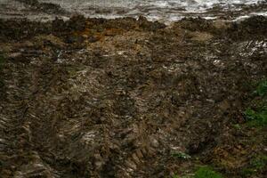 Pistes de véhicules lourds sur la surface de terre sous la pluie d'été photo