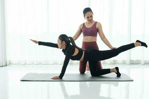 couple femme fabrication yoga ou aptitude des exercices. femme fabrication yoga avec entraîneur ou personnel entraîneur pour santé ou actif mode de vie. photo