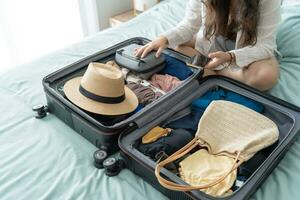 femme emballage valise sur lit pour une Nouveau périple emballage liste pour Voyage Planification en train de préparer vacances livre maintenant en voyageant transport photo