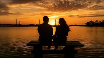 silhouette couple séance sur jetée à le coucher du soleil photo