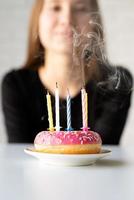 Fille d'anniversaire d'adolescent soufflant des bougies sur le beignet photo