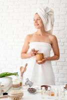 Femme en serviette de bain blanche à l'aide d'un mortier et d'un pilon en marbre photo