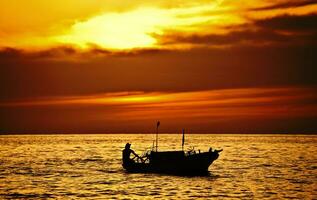 pêcheur sur le bateau plus de spectaculaire le coucher du soleil photo