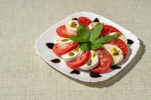 assiette de en bonne santé classique délicieux caprese sur une blanc assiette sur une lumière lin nappe de table clair espace photo