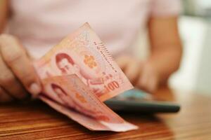 asiatique femme compte thaïlandais baht billet de banque argent et en portant dans main, investissement économie, comptabilité affaires et bancaire. photo