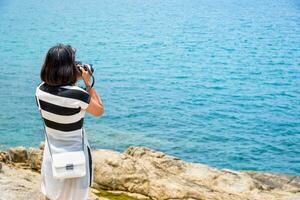 Jeune femme la photographie près le mer photo