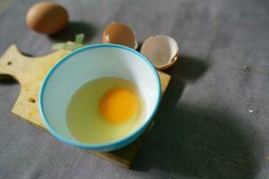 frit poulet des œufs prêt à cuisinier dans une bol avec une béton Contexte photo