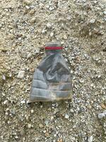 une Plastique bouteille rempli avec une des ordures mensonges sur le plage photo