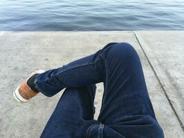 Jeune homme jambes dans jeans séance près le rivière photo