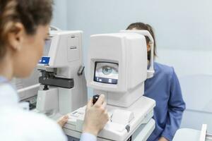 médecin essai pour yeux avec spécial optique appareil dans moderne clinique. ophtalmologiste examiner yeux de une patient en utilisant numérique microscope pendant une médical examen dans le ophtalmologique Bureau photo