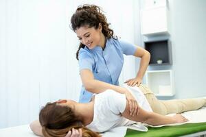 Jeune médecin chiropracteur ou ostéopathe fixation mensonge les femmes retour avec mains mouvements pendant visite dans Manuel thérapie clinique. professionnel chiropracteur pendant travail photo