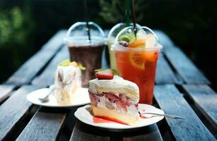 fait maison boulangerie pour fraise et kiwi fromage gâteau dans blanc plaque. Frais relaxation avec dessert et fruit smoothies, glacé café, glacé vert thé dans café photo