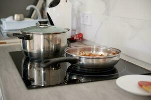 une inoxydable acier friture la poêle et casserole sur le électrique le fourneau dans le Accueil cuisine. culinaire concept. nourriture Contexte photo